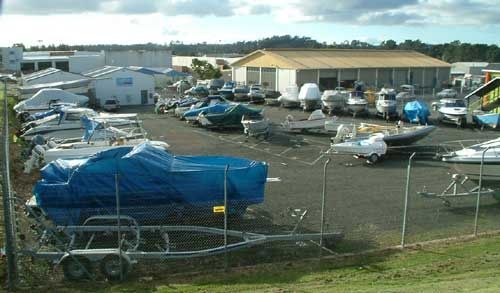 Boat storage facility entrance with boats on trailers behind chain-link fence